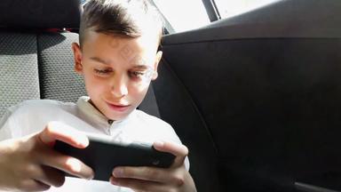 男孩玩智能手机开车车后座